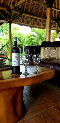 a bottle of wine and two wine glasses on a table at Ombak Resort at Ekas , a luxury surf and kite destination, Close to Inside Ekas beach in Ekas
