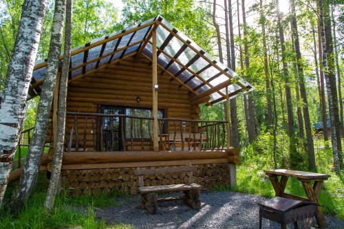 a log cabin in the woods with a porch and benches at База отдыха Берлога in Lumivaara