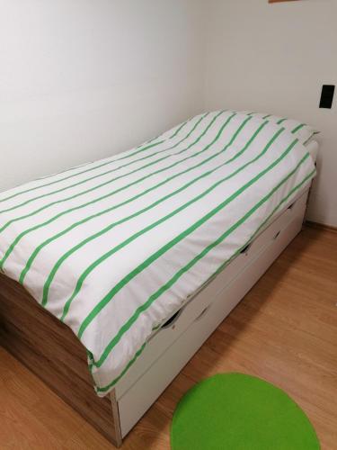 Cama en habitación con colchón verde y blanco en D&E Rooms, en Schwechat