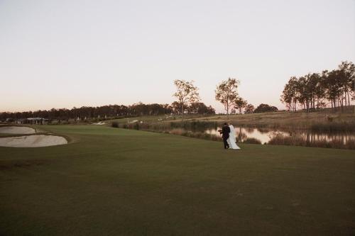a bride and groom standing on a golf course at Grand Mercure The Vintage in Pokolbin