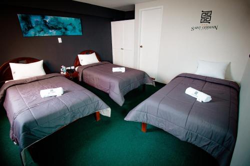 two beds in a room with green carpet at Saint Germain Hotel in Trujillo