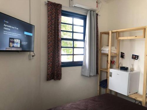 um quarto com uma janela e uma televisão na parede em Hospedaria Porto 27 em Porto Belo