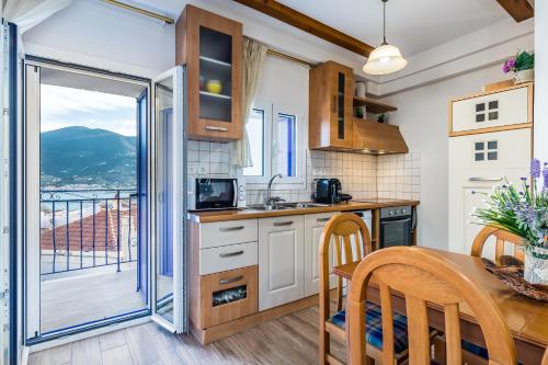 a kitchen with a table and chairs and a balcony at SUN NEST HOUSE in Skopelos Town