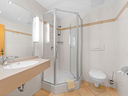 a bathroom with a shower and a sink and a toilet at Landhotel Gabriele in Unterwössen