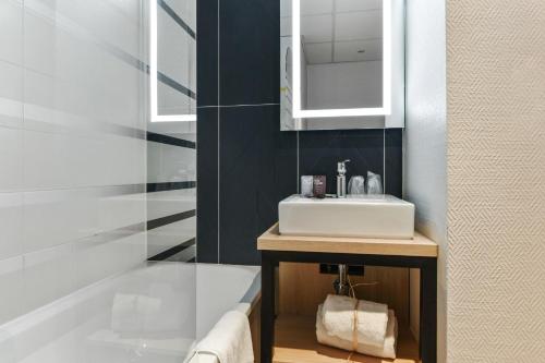 a bathroom with a white sink and a bath tub at Appart'City Confort Lille - Euralille in Lille