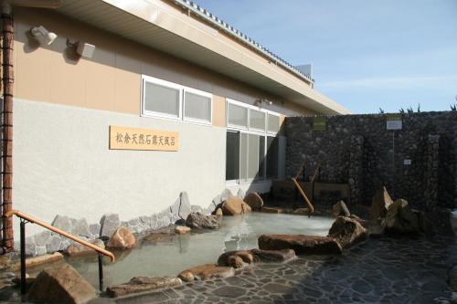 una piscina de agua frente a un edificio en Natural Onsen Hostel Hidamari no Yu en Takayama