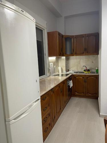 a kitchen with wooden cabinets and a white refrigerator at Apartament Gjergji in Sarandë