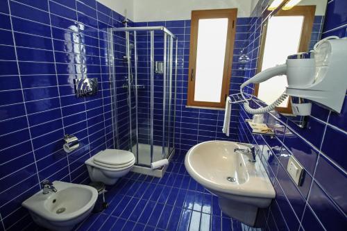 a blue tiled bathroom with a toilet and a sink at Hotel I Colori in SantʼAntìoco