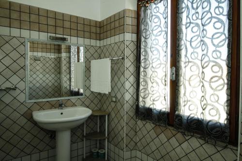 łazienka z umywalką, lustrem i oknem w obiekcie Hotel I Colori w mieście SantʼAntìoco