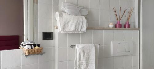 bagno con piastrelle bianche, asciugamani e specchio di Hotel Villa Platani a Riccione