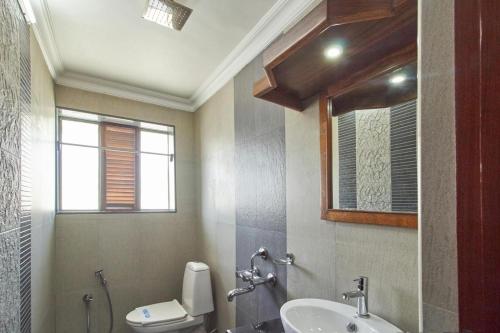 a bathroom with a sink and a toilet and a mirror at Hotel Mart View in Cochin