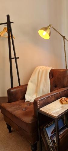 a living room with a brown couch and a lamp at The Family Tree in Whatstandwell