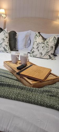 a tray on a bed with two cups and a remote control at The Family Tree in Whatstandwell