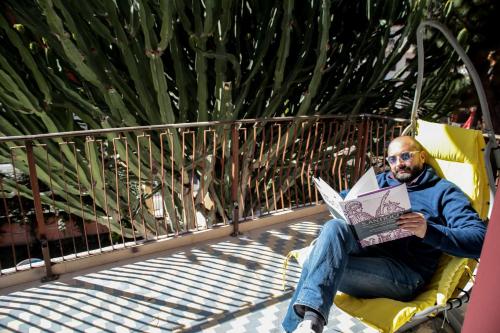 a man sitting in a chair reading a magazine at Hotel I Colori in SantʼAntìoco