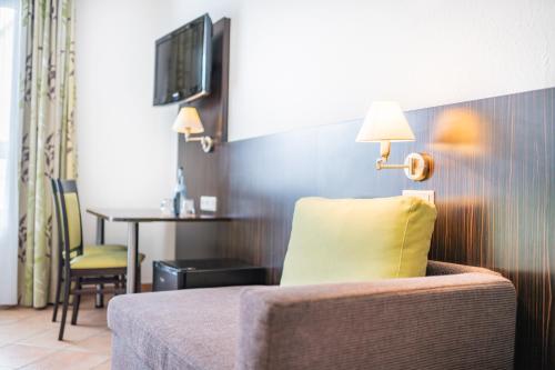 a hotel room with a chair and a table and a television at My Airport Hotel STUTTGART-AIRPORT-MESSE in Leinfelden-Echterdingen