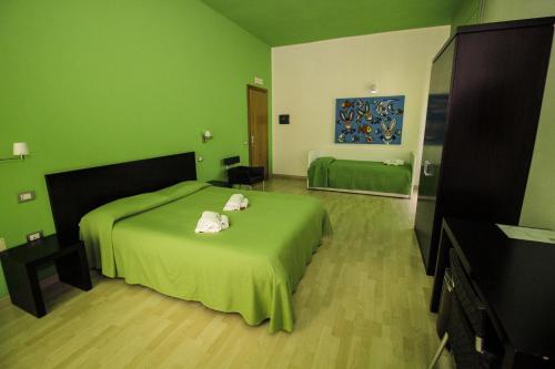 a green bedroom with a bed with two towels on it at Hotel I Colori in SantʼAntìoco