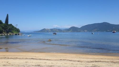 a beach with boats in a large body of water at Casa pé na areia em Angra dos Reis in Angra dos Reis