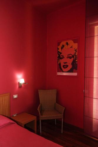 a red bedroom with a bed and a chair at Hotel I Colori in SantʼAntìoco