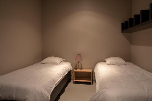 two twin beds in a room with a lamp on a table at Oud Gemeentehuis in Poelkapelle