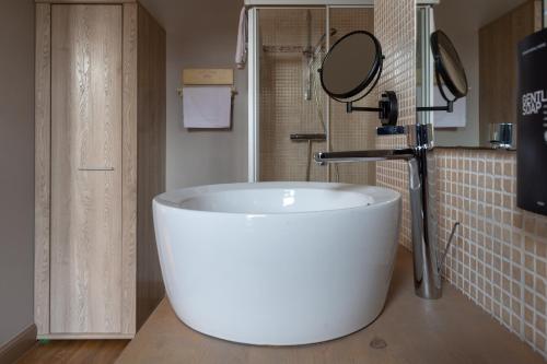 a large white tub in a bathroom with a mirror at Oud Gemeentehuis in Poelkapelle