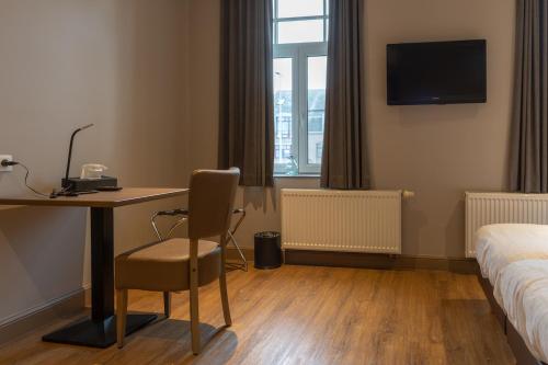 a hotel room with a desk and a bed and a bed and a room with at Oud Gemeentehuis in Poelkapelle