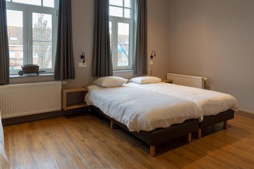 a bedroom with a large bed with two pillows on it at Oud Gemeentehuis in Poelkapelle