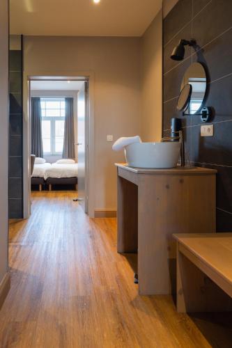 a bathroom with a sink and a mirror and a bedroom at Oud Gemeentehuis in Poelkapelle