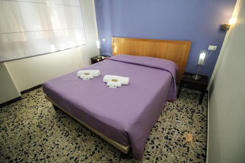 a bedroom with a purple bed with two objects on it at Hotel I Colori in SantʼAntìoco