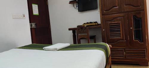 a room with a bed and a wooden cabinet at Hotel Mart View in Cochin