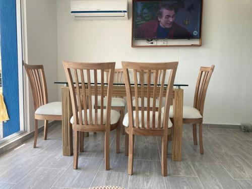 Una mesa de comedor con cuatro sillas y un televisor. en Apartamento en Ricaurte conjunto Puerto Azul Club House, en Ricaurte
