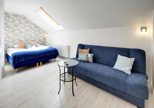 a living room with a blue couch and a bed at Apartamenty EverySky - Wilcza 3F-2 in Karpacz