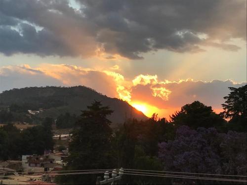 a sunset over a mountain with trees and buildings at Casa de las Escaleras in Pátzcuaro