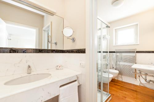 a white bathroom with a sink and a toilet at Hotel & Residence Exclusive in Marina di Carrara