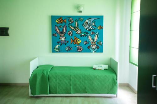 a bedroom with a green bed and a painting on the wall at Hotel I Colori in SantʼAntìoco