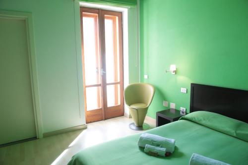 a bedroom with a bed and a chair and a window at Hotel I Colori in SantʼAntìoco