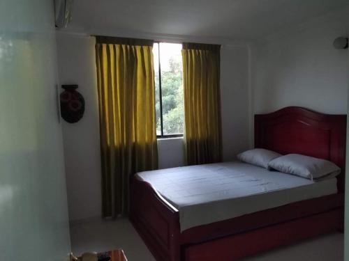 a bedroom with a bed and a window with yellow curtains at Acogedor apartamento a 15 metros del mar in Santa Marta
