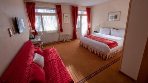 ジュネーヴにあるホテル デス ホルロガースのベッド1台と赤いソファ2台が備わるホテルルームです。