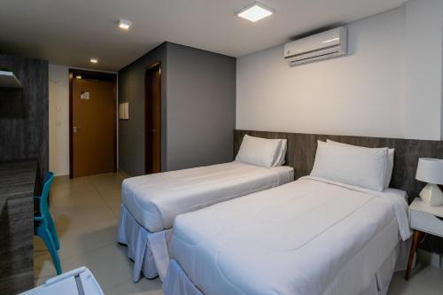 a hotel room with two beds and a table and a chair at Hotel Mais1 in Campina Grande