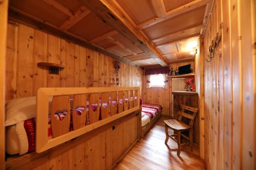 a log cabin bedroom with a bed and a ladder at Baita Medil in Predazzo