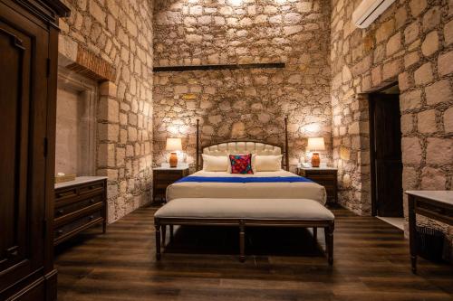 a bedroom with a bed and a stone wall at Casa Vieja Hotel Boutique in Morelia