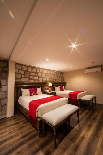 a hotel room with two beds and two chairs at Casa Vieja Hotel Boutique in Morelia