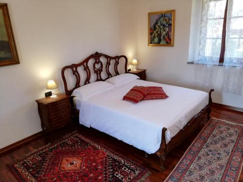 Schlafzimmer mit einem Bett mit weißer Bettwäsche und einem roten Teppich in der Unterkunft La Foresteria dei Baldi in Pavia