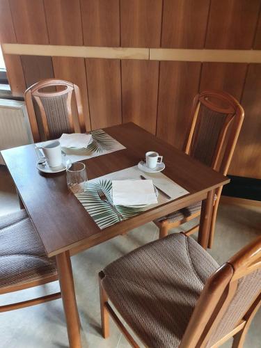 a wooden table with two cups and plates on it at Pension Stettiner Hof in Eggesin