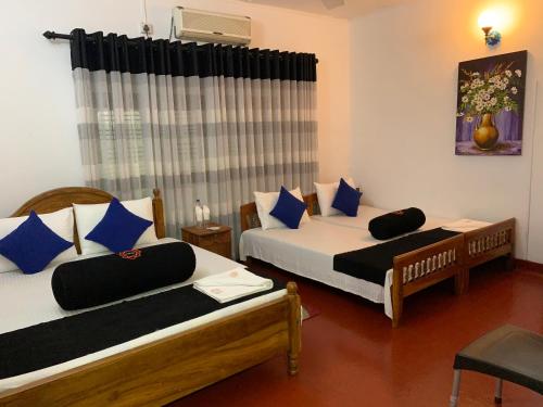 a bedroom with two beds with blue pillows at Sobha Holiday Home in Anuradhapura