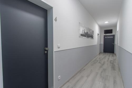 une porte ouverte menant à un couloir avec des murs blancs et du parquet. dans l'établissement Hotel Billard Center Weywiesen, à Bottrop