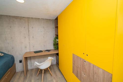 a bedroom with a yellow wall and a white chair at +MS +Loft Coworking +Vigilancia 24hrs +Internet y Amenities 408 in Laborcillas