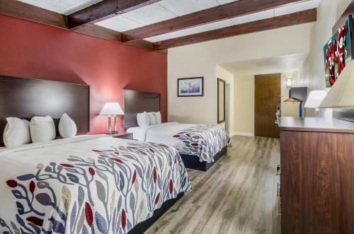une chambre d'hôtel avec deux lits et un mur rouge dans l'établissement Red Roof Inn Madison Heights, VA, à Lynchburg