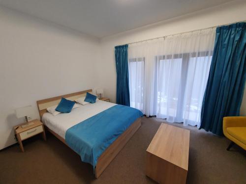 a bedroom with a bed with blue sheets and blue curtains at Pensiunea Black Mountain in Baia-Sprie