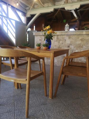 a wooden table and chairs with a vase of flowers on it at Makis Nest Apart-Hotel in Vourvourou