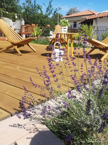 a wooden deck with purple flowers and a picnic table at Makis Nest Apart-Hotel in Vourvourou